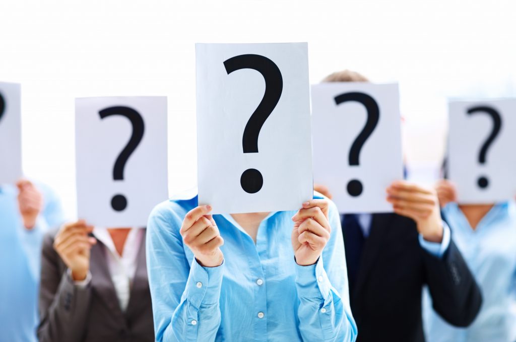 A group of people holding question mark signs over their faces so we can't see how they feel.