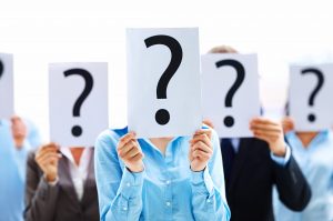 A group of people holding question mark signs over their faces so we can't see how they feel.